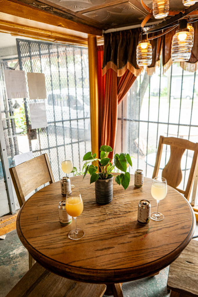 Table at Faubourg Wines with cans of St. Rains and two glasses poured, next to a window