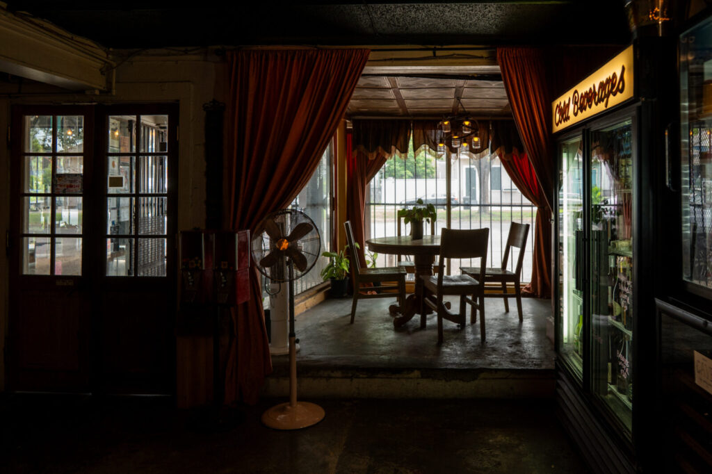Front room at Faubourg Wines with a Cold Beverages sign, cooler case, and cafe table by the window