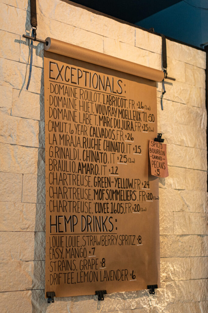 Handwritten menu at Pluck Wine Bar listing exceptional pours and a hemp drinks section