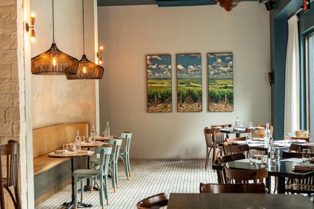 Close-up of a St. Rains Ojai Kush being poured into a glass at Pluck Wine Bar
Dining room at Pluck Wine Bar with pendant lights, banquette seating, and vineyard photographs on the wall