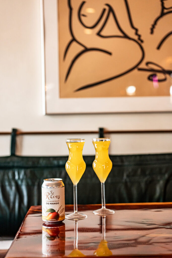 Can of St. Rains OG Mango with two cocktails on a table at Smoke & Honey